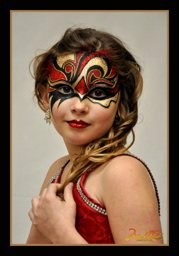 girl in a stylized red, gold, and black mask that matches her dress
